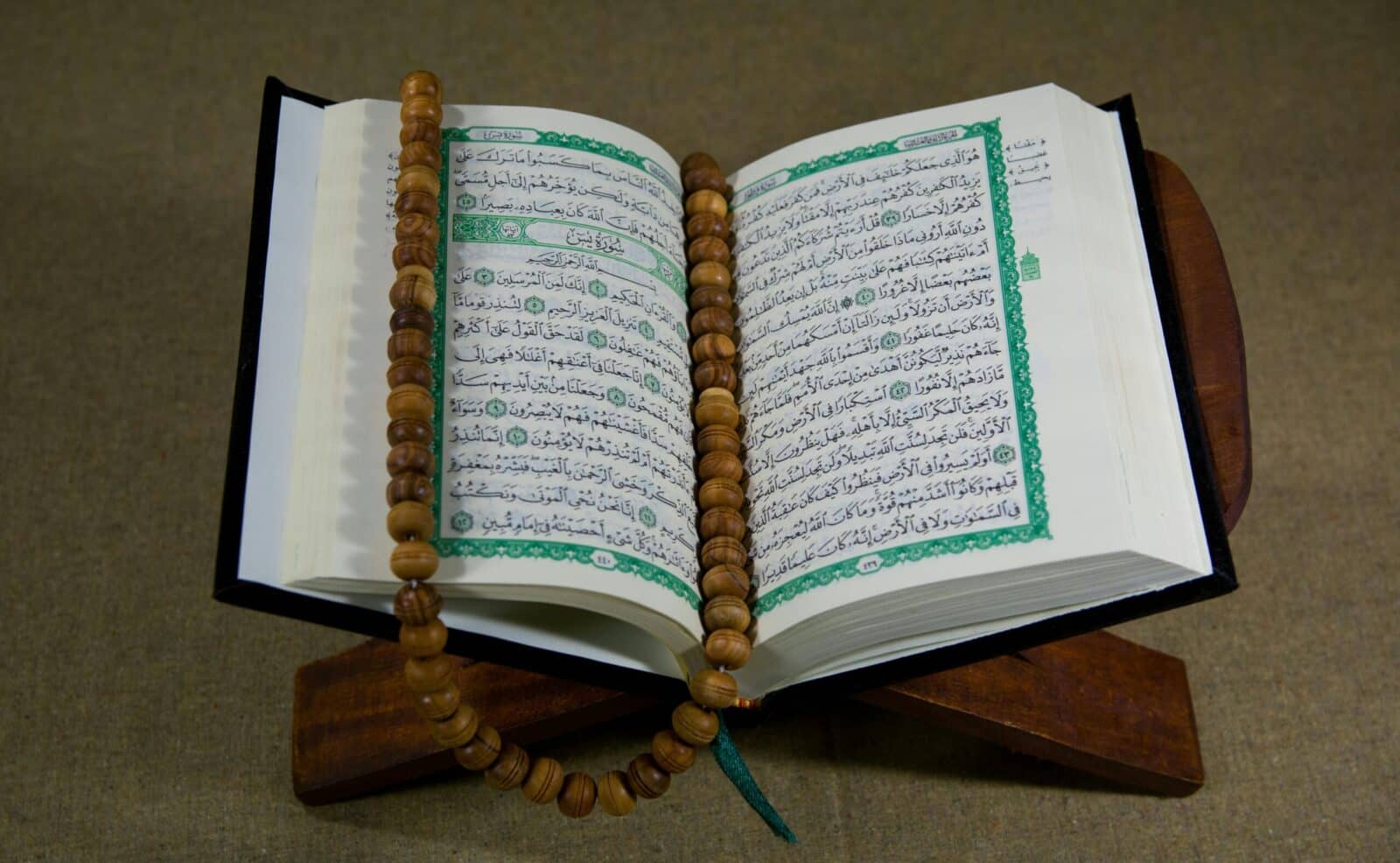 An open Quran with prayer beads displayed on a wooden stand, symbolizing Islamic faith and tradition.