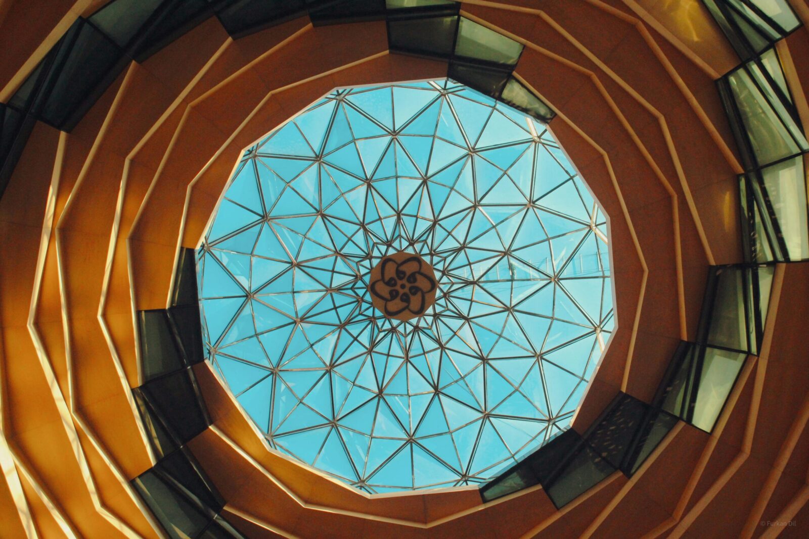 Interior view of a geometric glass dome with a blue sky background. Modern architectural design.