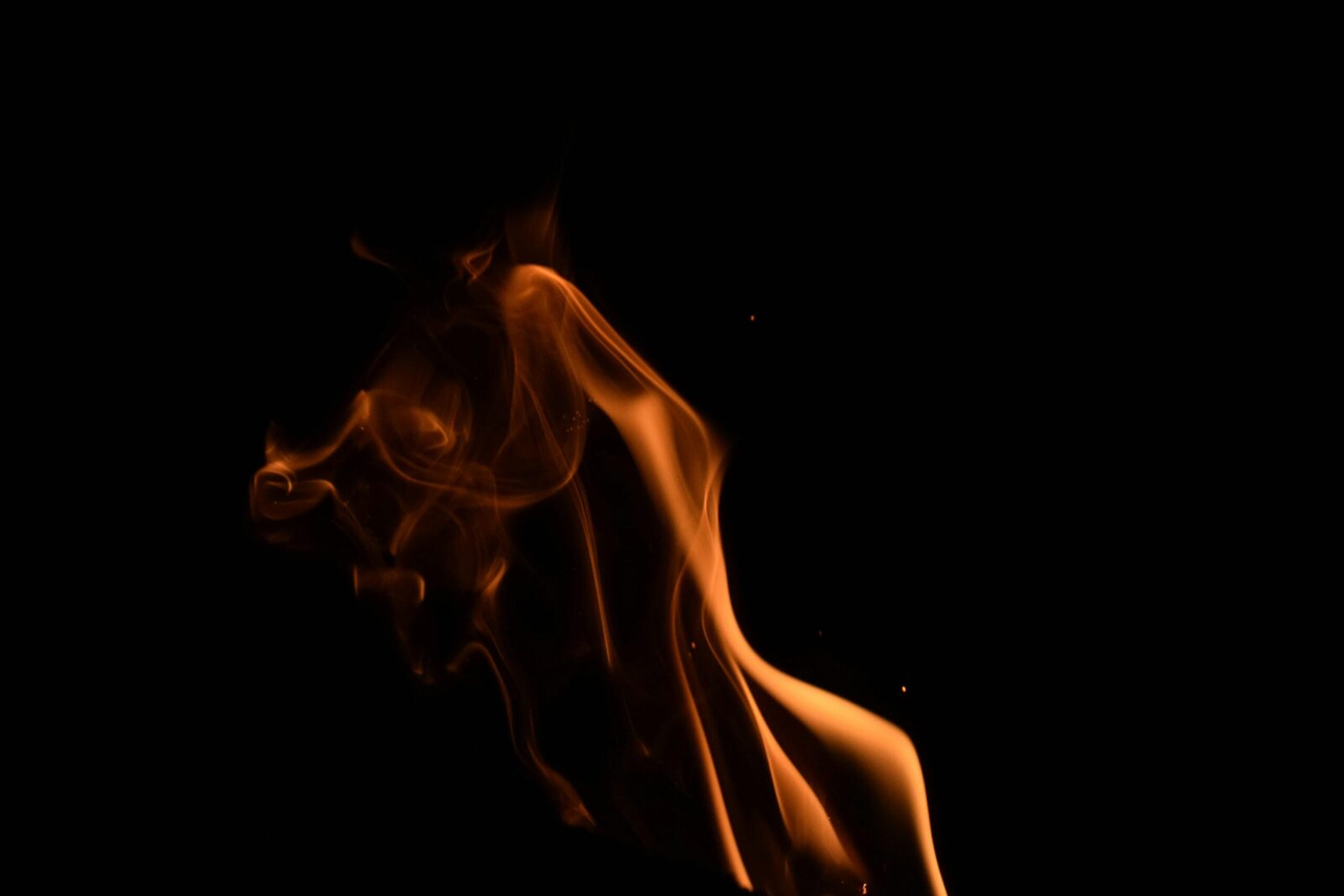 A captivating capture of an orange flame against a dark background, creating a dramatic and artistic effect.