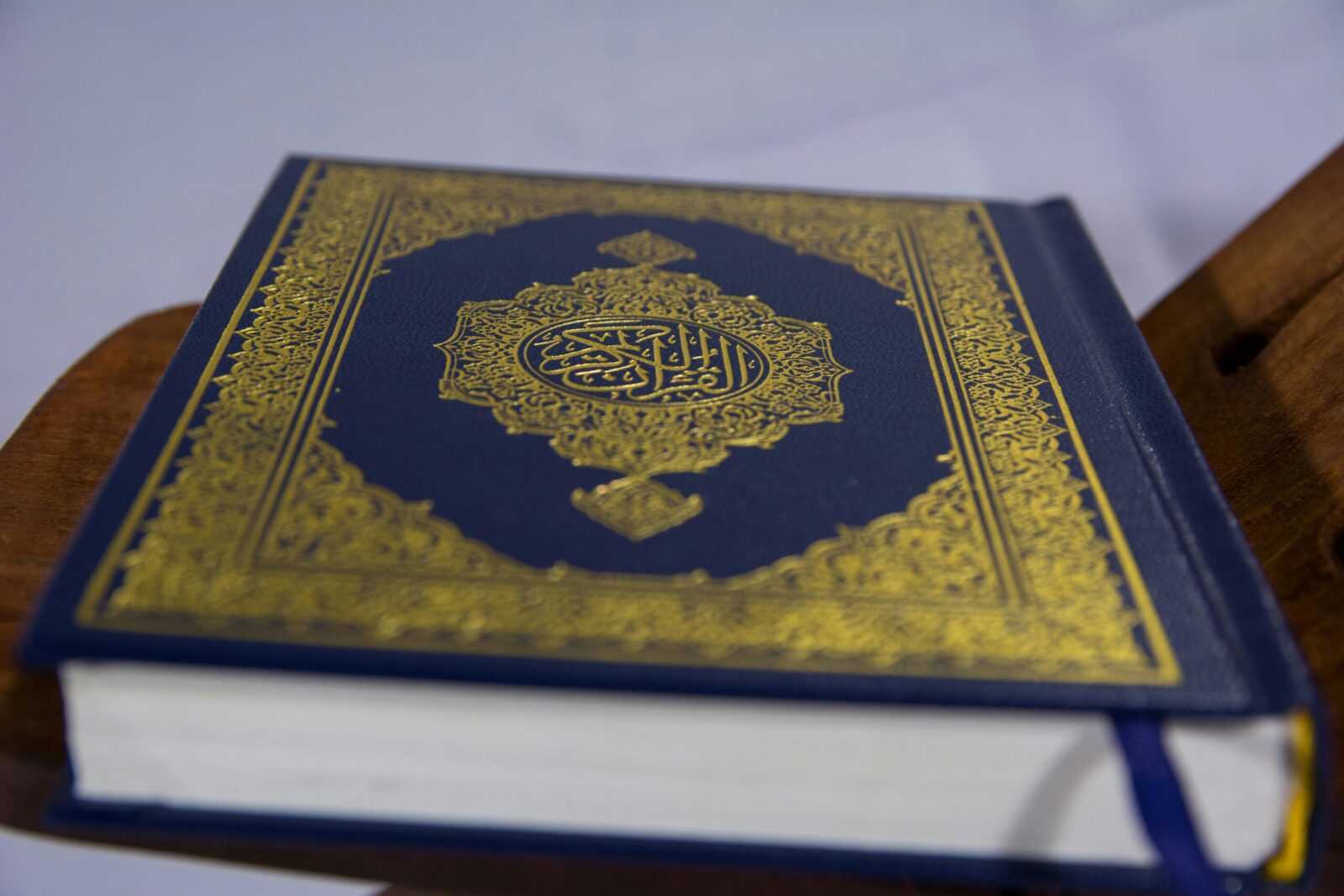 Close-up of Quran on stand, showcasing intricate Arabic calligraphy design.