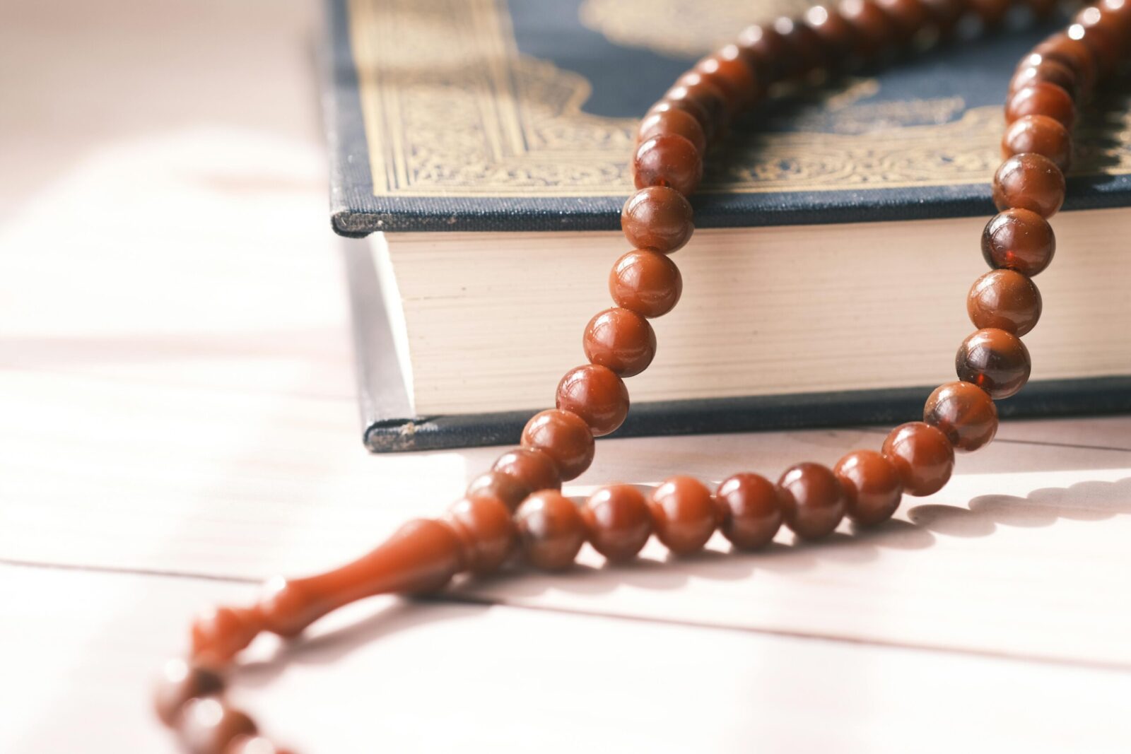 Detailed shot of Islamic prayer beads resting on a Quran, highlighting spiritual themes.