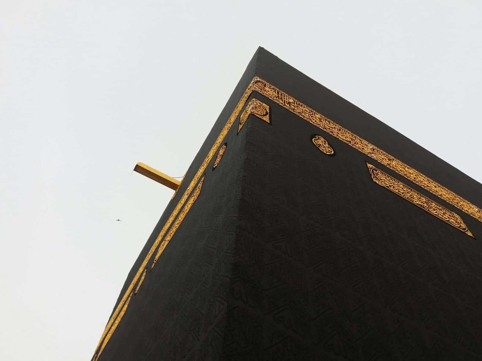 Close-up view of the Kaaba in Mecca, showcasing its intricate gold details against a clear sky.