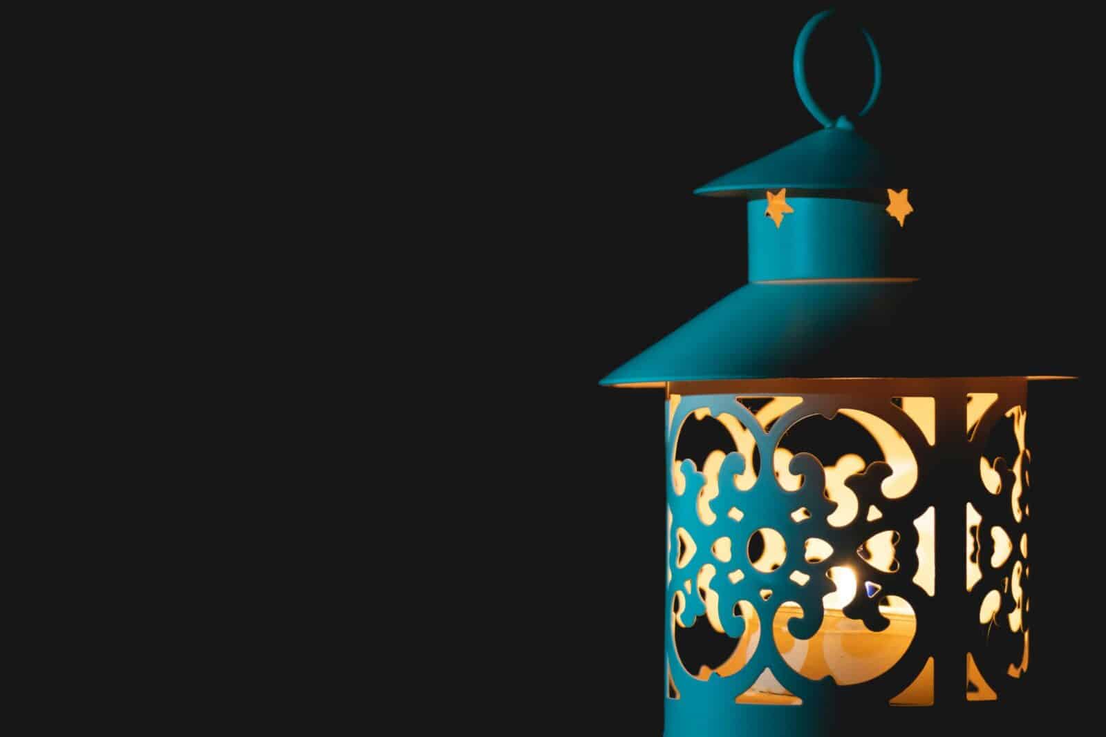 Close-up of a decorative lantern with candlelight, showcasing elegant patterns against a dark backdrop.