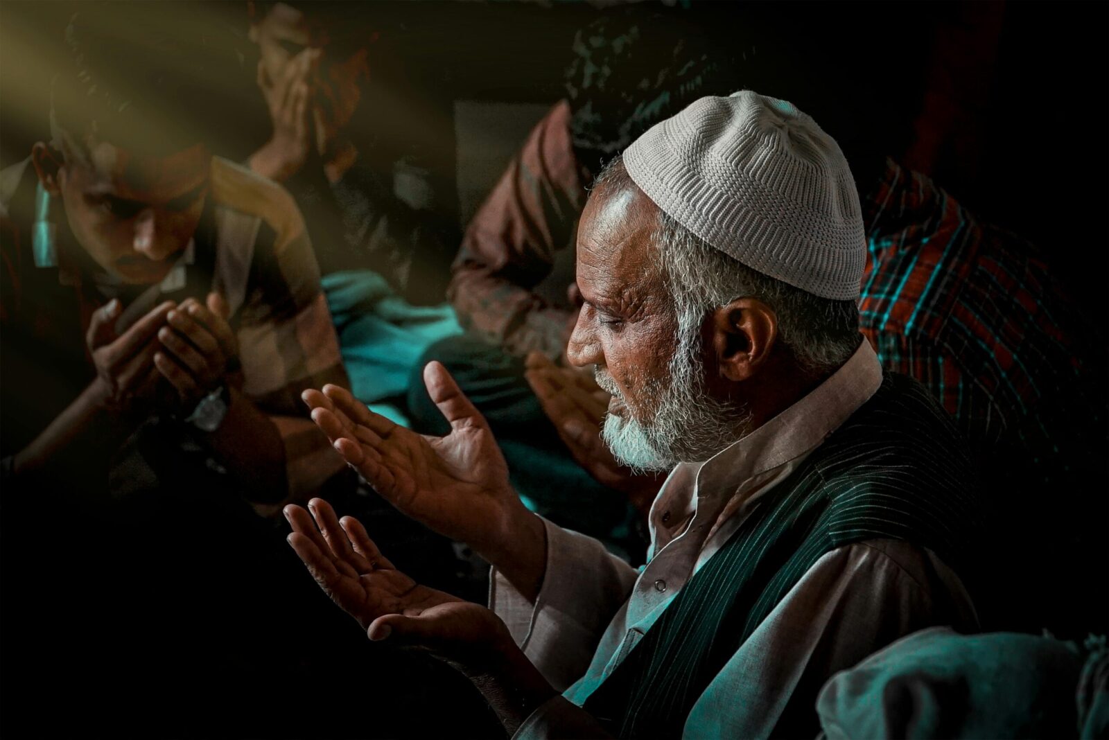Elderly man praying in a group setting, highlighting faith and devotion indoors.