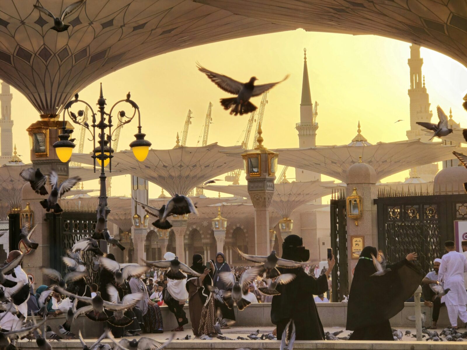 Captivating view of Al-Masjid an-Nabawi at sunset with pigeons in flight, symbolizing peace.
