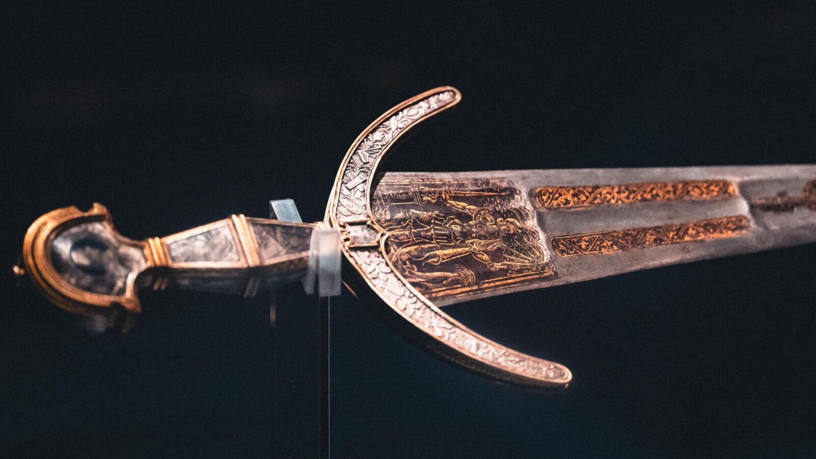 Close-up of an intricately designed historical sword with ornate details on blade and hilt.