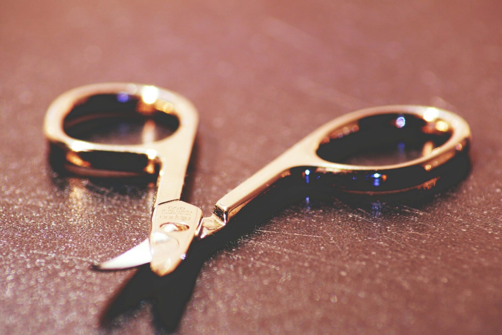 Close-up view of gold sewing scissors on a textured surface, showcasing sharp details.