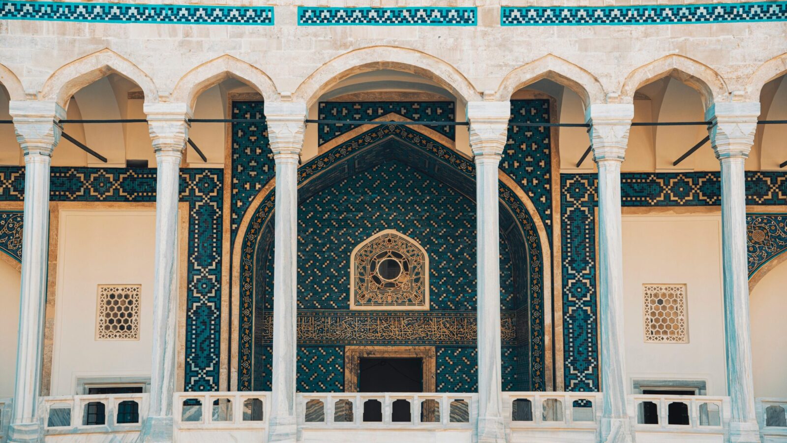 Stunning detailed view of a historic mosque facade with blue mosaic tiles and archways, showcasing Islamic artistry.