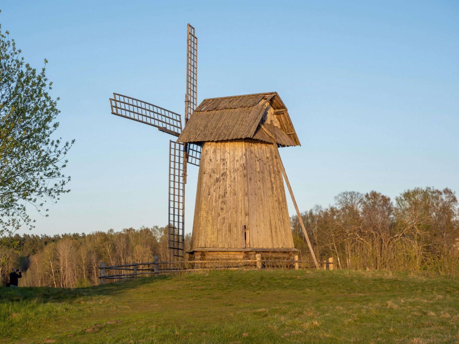 Charming rustic wooden windmill under clear blue skies in the countryside.