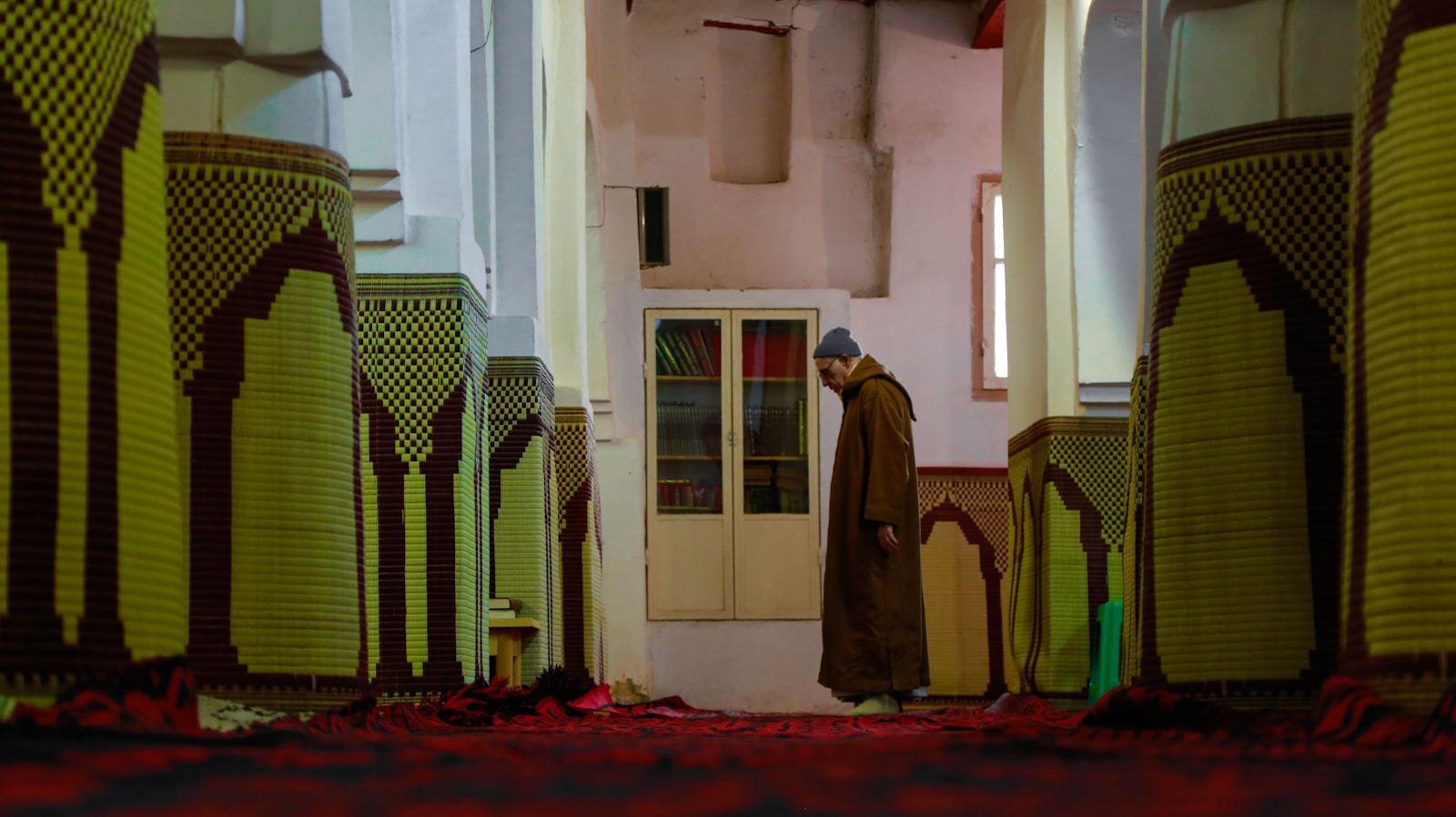 man in white thobe standing on red carpet